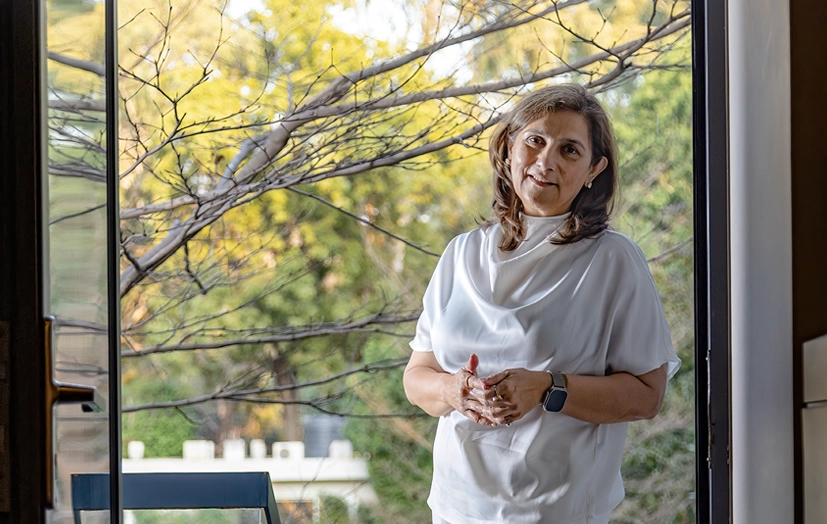 Monika Choudhary stands beside a glass window with trees outside for the GoodHomes India feature Five Points of Inspiration.
